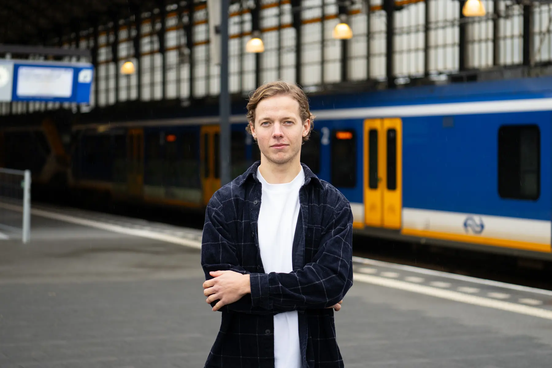 Roel staat naast een trein en kijkt naar de camera