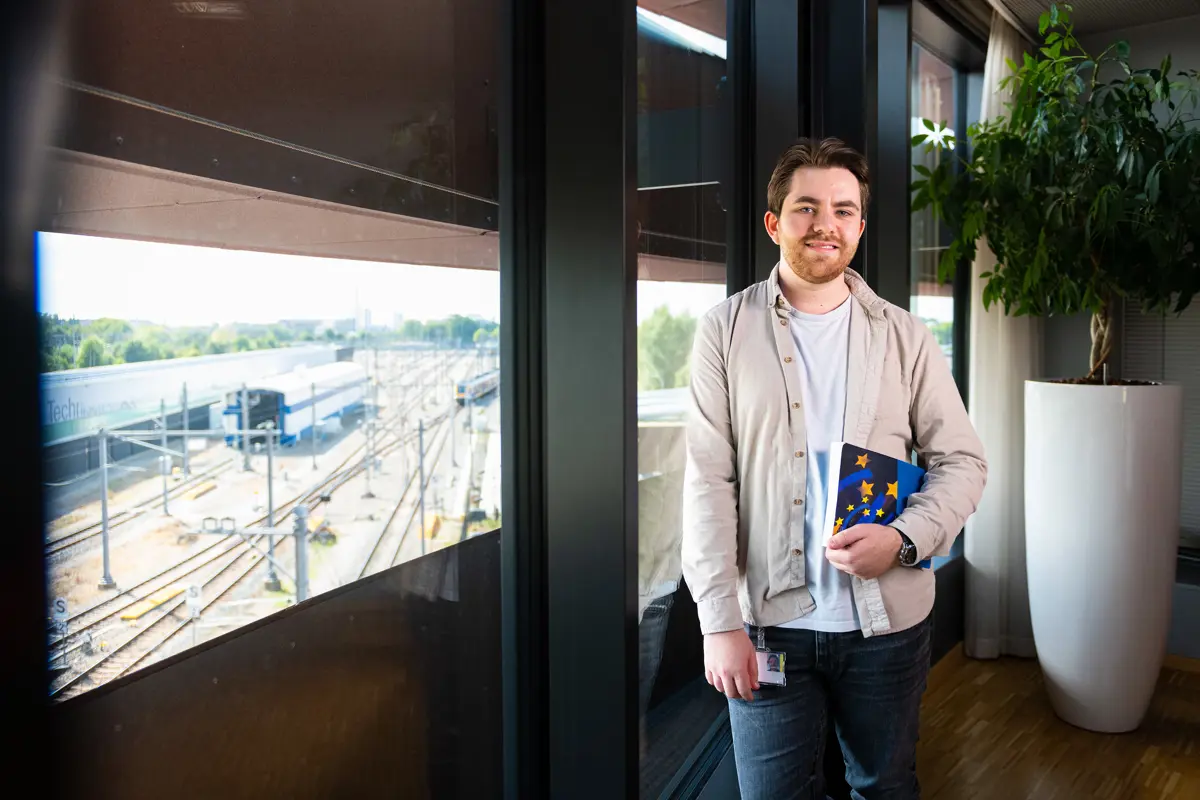 Robert-paul staat tegen een raam aan met uitzicht op het spoor